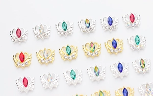 Détail macro de charmes à ongles en alliage avec motifs de couronne et strass colorés