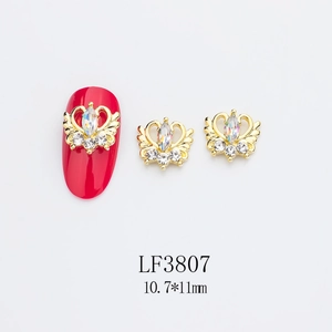 Vue détaillée de bijoux d'ongles couronne dorée avec strass sur manucure rouge