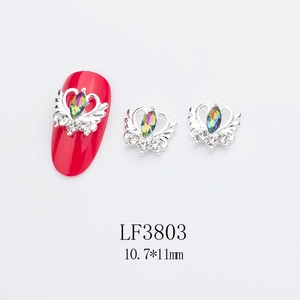 Détail d'un bijou d'ongle en alliage avec strass AB sur un faux ongle rouge vif