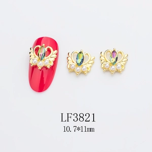 Détail d'un bijou d'ongle couronne dorée 3D avec cristal marquise et perles sur rouge