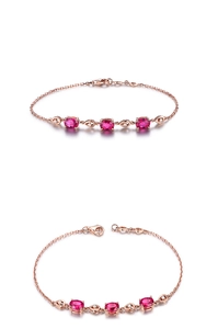 Detail view of rose gold bracelet with oval red gemstones and small diamond accents