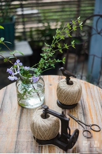 Close-up of vintage cast iron bird twine holder and metal scissors on a wooden table