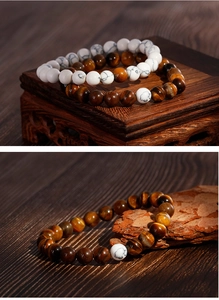 Macro detail of tiger eye and white turquoise beaded bracelets on a rustic wood base