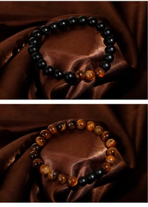 Detail view of tiger eye and matte black beaded bracelets on dark silk background