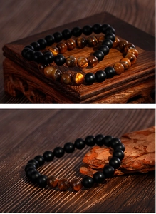 Detail view of tiger eye and matte black agate beads on a vintage wooden surface