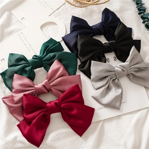 Detail view of multi-color satin bow hair clips in navy, green, grey, pink, and burgundy