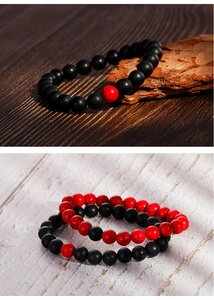 Detailed view of matte black onyx and red marble beads on a rustic wooden background
