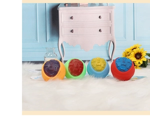 Close-up of four colorful textured rubber dog balls for chewing on a soft white rug