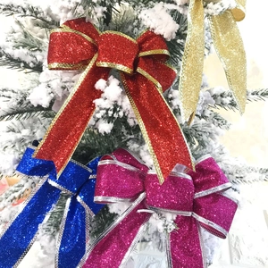 Close-up of glittery Christmas bows in multiple colors on a snowy pine tree branch