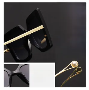 Detail of oversized sunglasses featuring gold metal temples and elegant pearl end tips