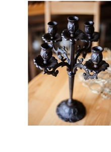 Detail van vijfarmige gietijzeren kandelaar met vintage krulwerk op houten tafel