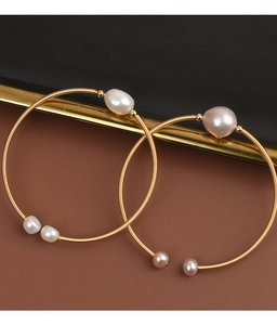 Close-up of gold wire wrapped bracelets featuring natural white and pink freshwater pearls