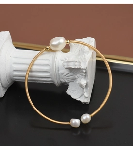 Detail of handmade gold wire-wrapped open cuff bracelet with three natural freshwater pearls
