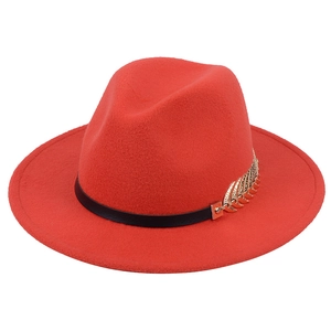 Detail of red wool fedora hat featuring a black leather band and golden leaf metal ornament