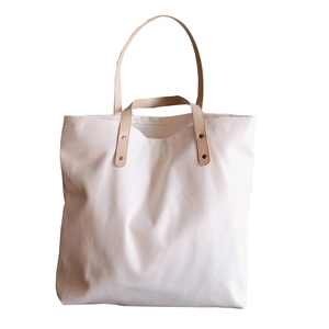 Large white canvas tote bag with brown PU leather handles and metal rivet details