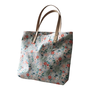 Floral print tote bag in light blue-grey fabric with stylish khaki leather handles