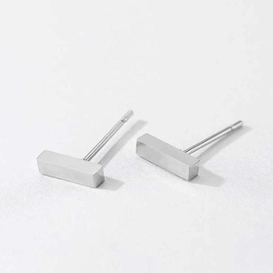 Macro shot of silver minimalist rectangular stainless steel stud earrings on white surface