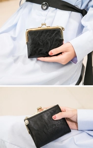 Close-up of vintage black oil-wax leather mini wallet with gold kiss-lock closure detail