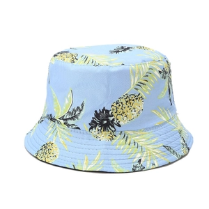 Detail of light blue cotton bucket hat featuring vibrant yellow pineapple print and stitching