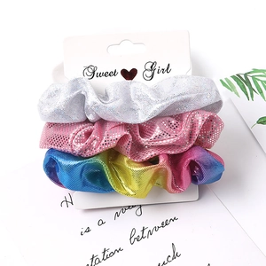 Three sparkly fabric scrunchies in silver, pink, and rainbow colors on a Sweet Girl card