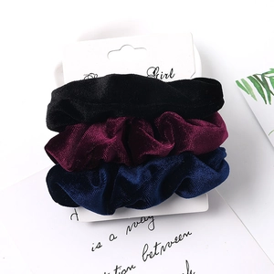Detailed view of velvet scrunchies set in black, burgundy and navy on display card