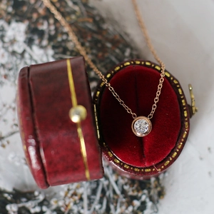 Close-up of sparkling zircon solitaire pendant in a vintage red velvet jewelry box