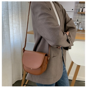 Lifestyle-Ansicht einer braunen Leder-Satteltasche kombiniert mit einem grauen Blazer