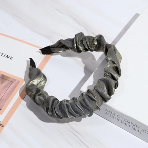 Detail of grey pleated fabric headband with metallic sheen on marble background