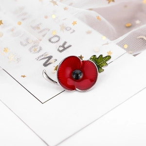 Detailed macro view of red poppy brooch with rhinestone and green leaf on white mesh