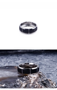 Detail of silver stainless steel ring with black matte blocks on a dark stone background
