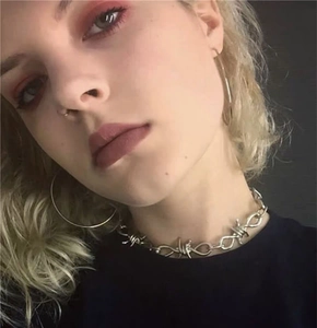 Close-up of silver thorn link chain necklace and hoop earrings on model in punk style