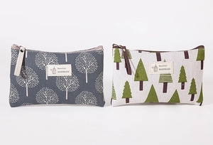 Close-up of canvas makeup bags with tree patterns and handmade tags in grey and beige
