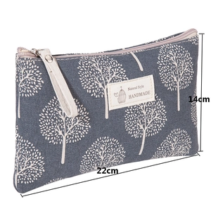 Detail view of large grey canvas makeup bag with tree pattern and 22cm x 14cm dimensions