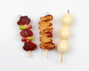 Close-up of realistic artificial meat skewer, sausage, and egg food keychain pendants