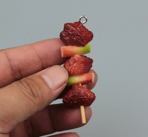 Macro shot of realistic miniature BBQ meat skewer keychain with detailed texture