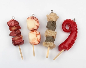 Detailed view of realistic resin food skewers with metal rings on a white background