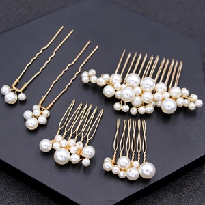 Five-piece gold bridal hair comb and pin set with elegant white pearls on black tray