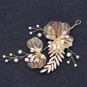 Detail view of handmade gold wire flower hairpiece with white pearls on black background