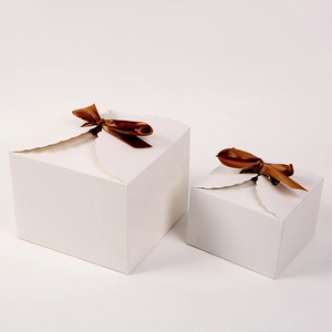 Detail of square white cardboard gift boxes with decorative brown ribbon bows