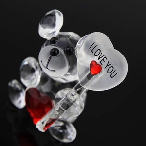 Macro shot of faceted clear crystal bear figurine holding a red heart with I Love You text