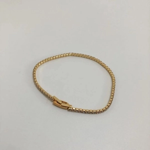 Macro detail of slim gold tennis bracelet featuring round white cubic zirconia stones