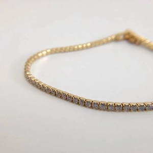 Macro shot of minimalist gold tennis bracelet with tiny clear cubic zirconia stones