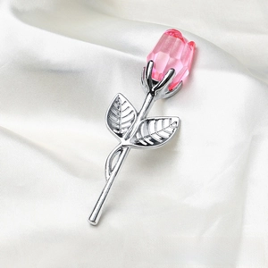 Detailed close-up of pink crystal rose with silver metallic stem on white silk