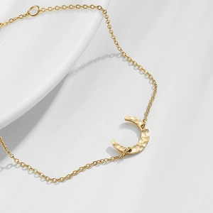 Minimalist gold moon pendant bracelet with hammered texture on a delicate link chain