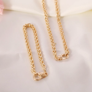 Detail of gold metal woven chain necklace and bracelet set on white silk background