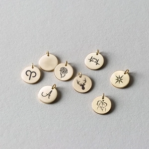 Macro detail of 9mm gold plated stainless steel pendants with engraved animal and star motifs