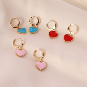 Three pairs of heart-shaped enamel drop earrings in blue, red, and pink on silk fabric
