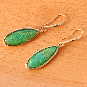 Detailed macro shot of gold teardrop earrings with emerald green textured stones