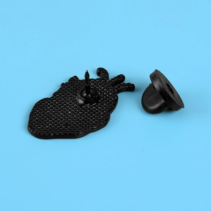 Detail view of the anatomical heart badge back with secure black rubber clutch on blue background