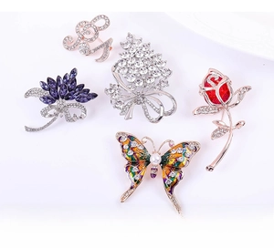Detailed close-up of crystal butterfly and floral alloy brooches with pearls and rhinestones